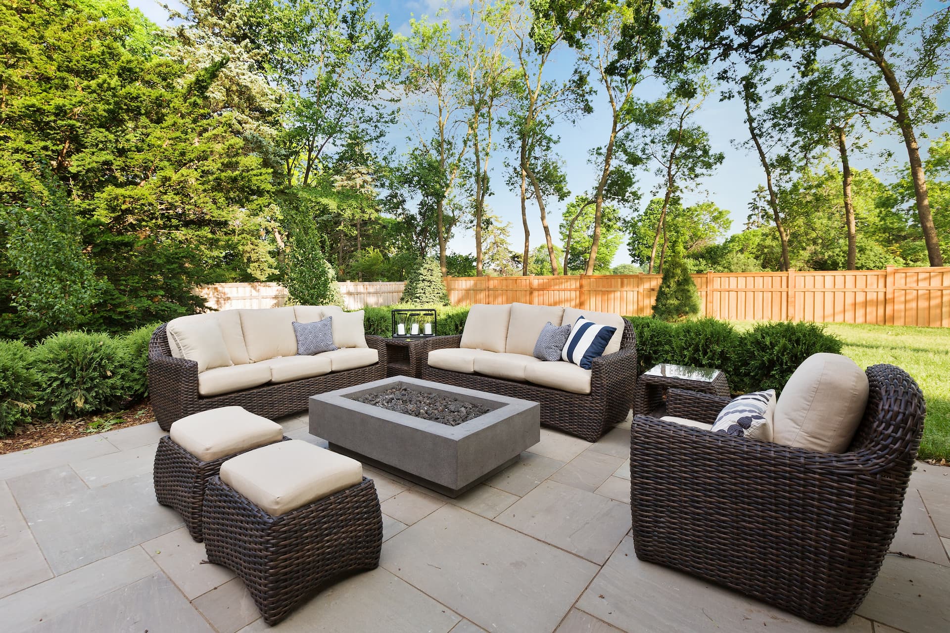 Luxury outdoor patio with wicker furniture, fire pit, and stone flooring